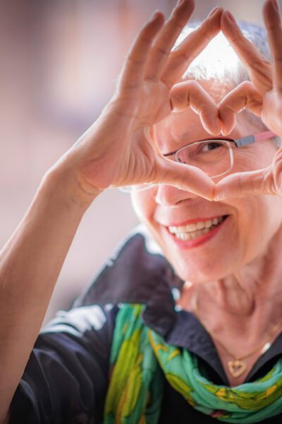 Cute senior old woman making a heart shape with her hands and fingers