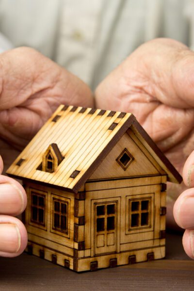 Old man protecting house model with hands .Risk insurance .The concept of mortgages and Bank loans. Poverty. Rental property.